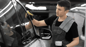 man removing water spots on dark car paint